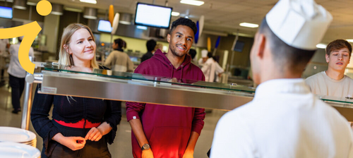 Zwei Personen stehen in der Mensa an der Essensausgabe.