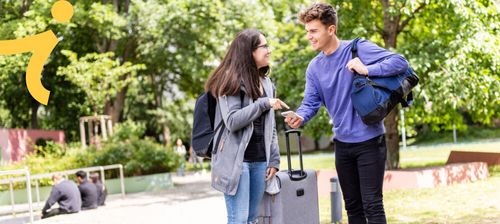 Zwei Studierende mit Gepäck unterhalten sich miteinander
