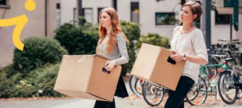 Zwei Studentinnen tragen je einen Umzugskarton