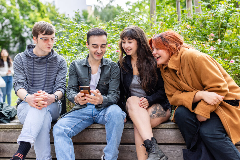 Vier Studierende schauen gemeinsam auf ein Smartphone